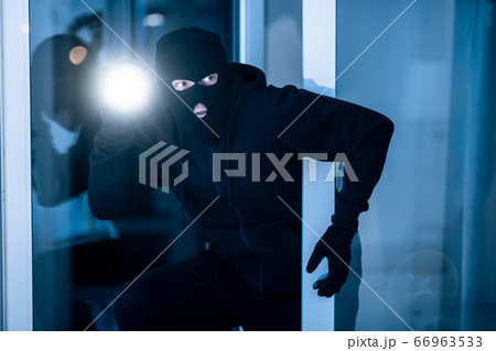 Thief breaking into apartment to steal, using torch 66963533