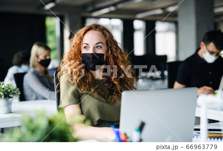 Young woman with face mask back at work in office after lockdown. Young woman with face mask back at work in office after lockdown. 66963779