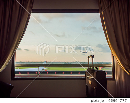 The window of the hotel near the airport and the plane taking off in the background of a suitcase or luggage. The window of the hotel near the airport and the plane taking off in the background of a suitcase or luggage. 66964777