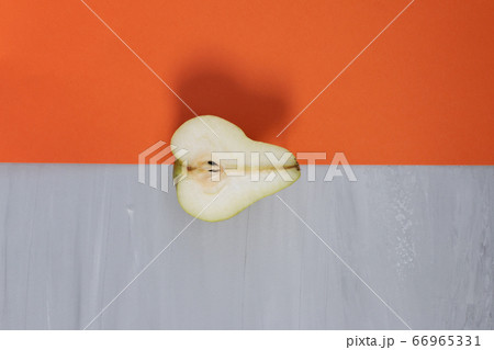 Over ripe half green delicious pear against orange and grey background. Design template, organic concept Over ripe half green delicious pear against orange and grey background. Design template, organic concept 66965331