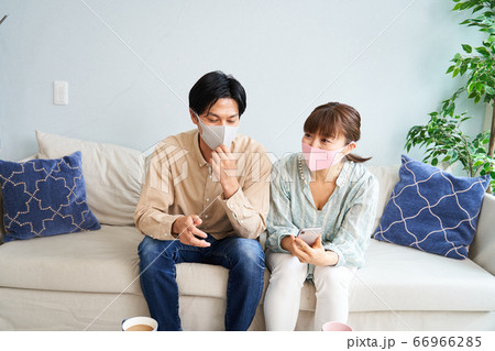 リビングでマスクをして感染対策をしてくつろぐ男女 リビングでマスクをして感染対策をしてくつろぐ男女 66966285