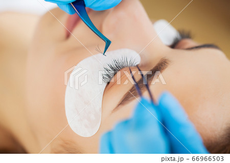 Close-up master of eyelash extensions extends eyelashes to a beautiful woman Close-up master of eyelash extensions extends eyelashes to a beautiful woman 66966503