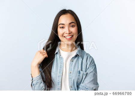 Lifestyle, people emotions and beauty concept. Carefree young asian woman talking and smiling, touching hair, recommend haircare products or beauty salon, white background 66966780