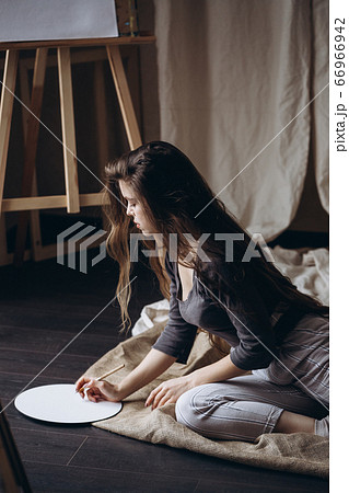 Brunette girl sitting on the floor draws with a brush 66966942
