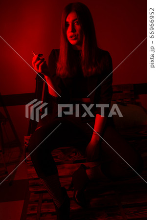 Girl model smokes vape in red light. 66966952