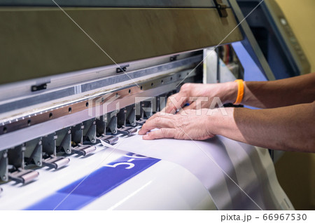 Technician catching a vinyl paper on large inkjet 66967530