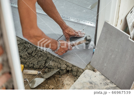 Hand of tiler laying and use mallet knocking Hand of tiler laying and use mallet knocking 66967539
