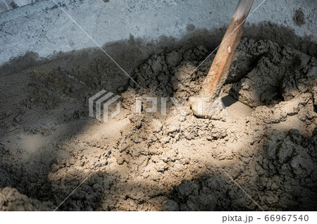 Hoe mixing cement, sand and water in bucket Hoe mixing cement, sand and water in bucket 66967540