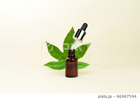 Glass bottle with pipette of herbal CBD oil, THC tincture and hemp leaf on pastel beige background. Glass bottle with pipette of herbal CBD oil, THC tincture and hemp leaf on pastel beige background. 66967594