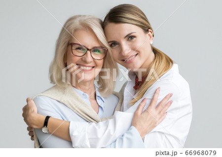 Happy older mother and adult daughter embracing looking at camer Happy older mother and adult daughter embracing looking at camer 66968079