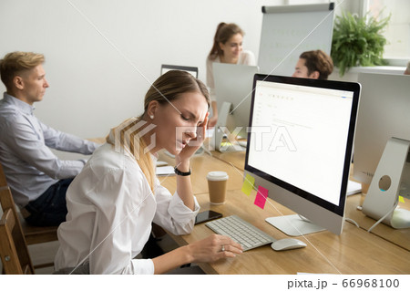 Exhausted female employee suffering from headache touching templ 66968100
