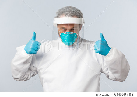 Covid-19, preventing virus, healthcare workers and vaccination concept. Confident doctor working with coronavirus patients in personal protective equipment, show thumb-up, assure everything alright 66969788