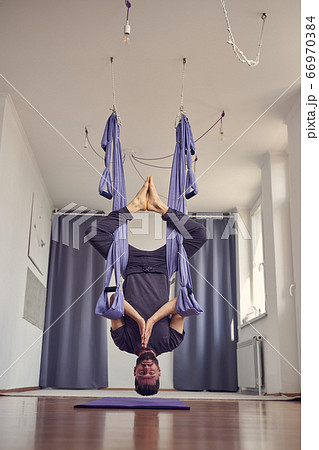 Bearded man hanging upside down and doing prayer pose 66970384