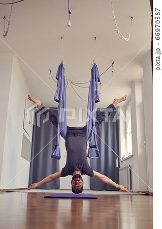 Bearded young man hanging upside down in yoga studio 66970387