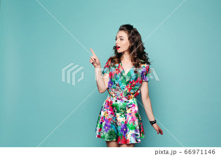 Pretty girl in floral dress pointing with finger. Pretty girl in floral dress pointing with finger. 66971146