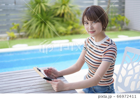 プールサイドでタブレットを見る女性 66972411