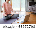 Sporty woman watching meditation tutorial on laptop and doing yoga at home.  66972708