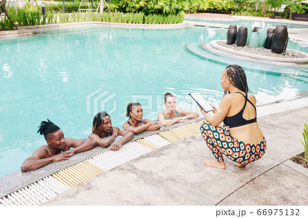 Woman reading to people in pool Woman reading to people in pool 66975132