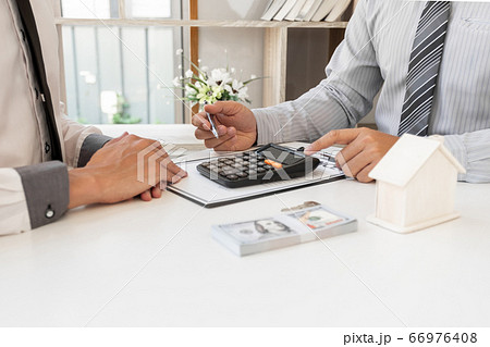 A real estate agent with House model is talking to clients about buying home insurance. Home insurance concept A real estate agent with House model is talking to clients about buying home insurance. Home insurance concept 66976408