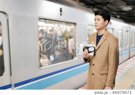 Asian man holding surgical face mask and map to protect covid-19 virus while waiting for the train Asian man holding surgical face mask and map to protect covid-19 virus while waiting for the train 66979073