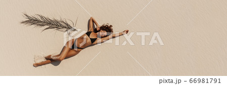 Top Aerial Drone View of Woman in Swimsuit Bikini Relaxing and Sunbathing on Beach 66981791