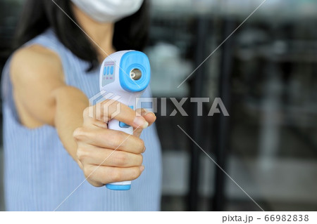 Staff wearing protecting face mask use non contact digital thermal scanner temperature gun at entrance. Concept of protection Covid flu. Control people to enter shopping mall, supermarket, canteen. Staff wearing protecting face mask use non contact digital thermal scanner temperature gun at entrance. Concept of protection Covid flu. Control people to enter shopping mall, supermarket, canteen. 66982838