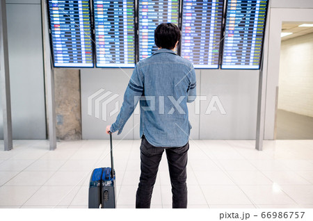 Asian man tourist at arrival departure board in 66986757