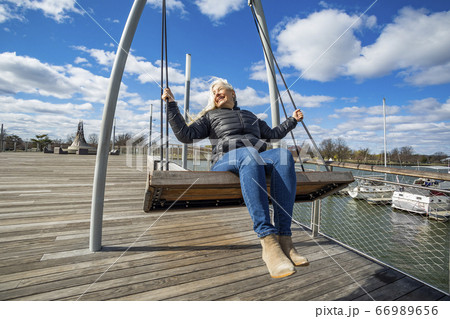 USA, Washington D.C., Senior woman on swing at Wharf District along Potomac River 66989656