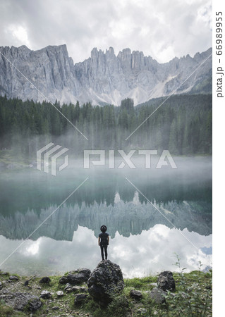 Italy, Carezza, Young man standing and looking at Lago di Carezza in Dolomites 66989955