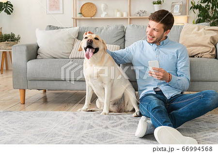 Portrait of young man with dog using cell phone 66994568
