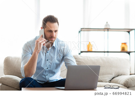 Portrait of successful businessman using phone and pc 66994821