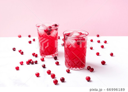 Cranberry cocktail in crystal glasses with ice decorated by berries on white bright marble table. Copy space. 66996189