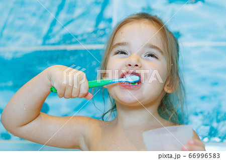 a little girl brushes her teeth and rinses her mouth in the bathroom. portrait of a child with a toothbrush a little girl brushes her teeth and rinses her mouth in the bathroom. portrait of a child with a toothbrush 66996583