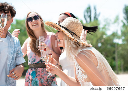 Seasonal feast at beach resort. Group of friends celebrating, resting, having fun on the beach in sunny summer day 66997667