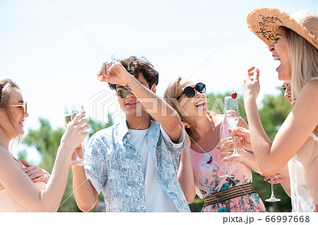 Seasonal feast at beach resort. Group of friends celebrating, resting, having fun on the beach in sunny summer day Seasonal feast at beach resort. Group of friends celebrating, resting, having fun on the beach in sunny summer day 66997668
