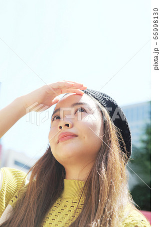 まぶしそうに上を見る若い女性 66998130