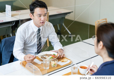 アクリルパーティションをはさんで食事する人々　飲食店の感染対策 66998310