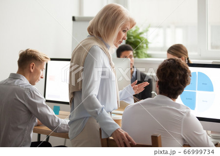 Senior female executive mentor supervising computer work of youn Senior female executive mentor supervising computer work of youn 66999734