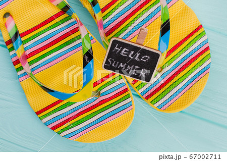 Fashion beach flip flops with little chalkboard on azure background. Fashion beach flip flops with little chalkboard on azure background. 67002711
