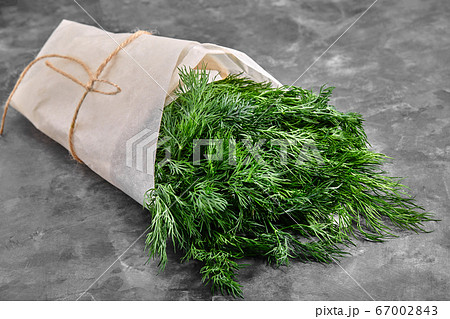 A bunch of fresh dill in craft paper on a stone surface. Useful and useful dill. A bunch of fresh dill in craft paper on a stone surface. Useful and useful dill. 67002843