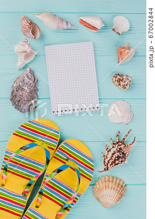 Flat lay composition with sandals, seashells and notepad. 67002844