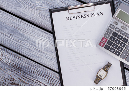Clipboard with business plan sheet and calculator on white wooden table. 67003046