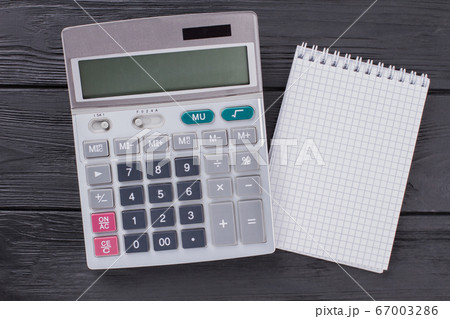 Calculator and notepad on dark wooden table. 67003286