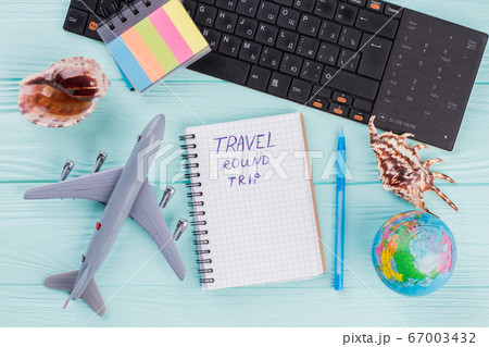 Flat lay composition with airplane, globe, seashells and notepad on blue desk. 67003432