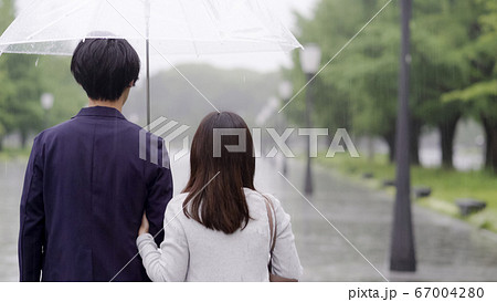 雨の日に傘を差してデートするカップルの写真素材