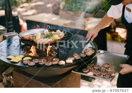 The chef grills meatballs for mini burgers on the grill. The chef grills meatballs for mini burgers on the grill. 67007637