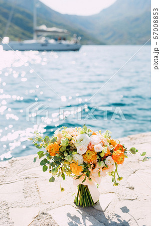 bridal bouquet of cream roses, eucalyptus tree branches, yellow and orange buttercups, not blooming buds of white flowers and ribbons on the pier by the sea bridal bouquet of cream roses, eucalyptus tree branches, yellow and orange buttercups, not blooming buds of white flowers and ribbons on the pier by the sea 67008853