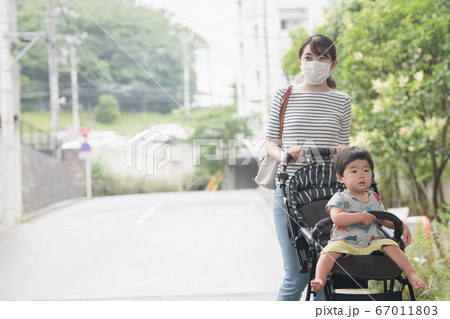 マスクをしてベビーカーを押す母親と男の子赤ちゃんの日本人親子イメージの写真素材