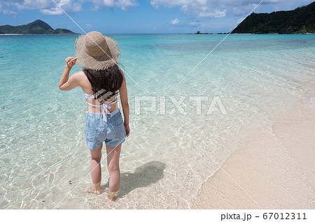 南国の海と麦わら帽子の女性の後ろ姿イメージ 撮影地 奄美大島 の写真素材