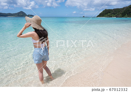 南国の海と麦わら帽子の女性の後ろ姿イメージ 撮影地 奄美大島 の写真素材